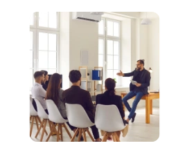 reunião de pessoas com um mentor a frente explicando e movimentando as mãos.